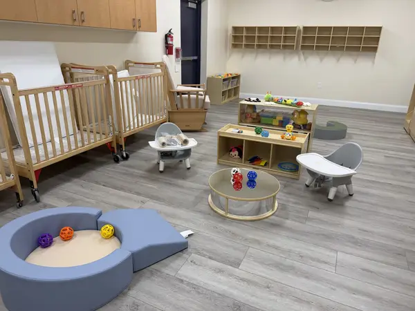 Infant room at the Midway Blvd location with cribs and a soft play area