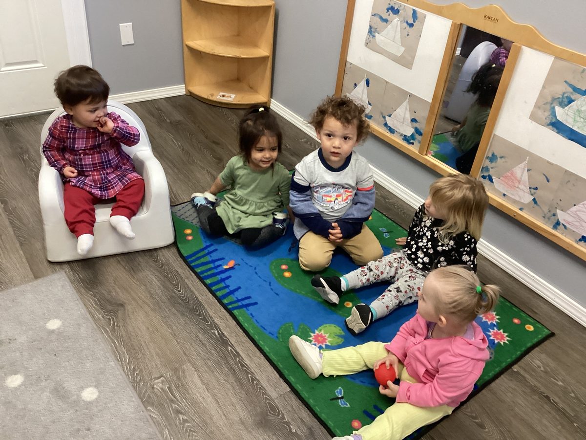 Young toddlers sitting together on a rug during circle time