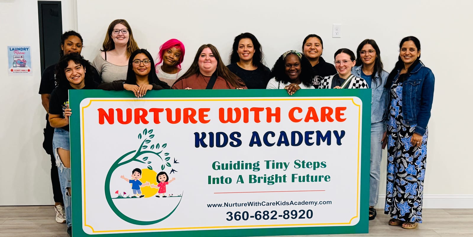 Some of the Nurture with Care Kids Academy team holding the academy sign at the Midway Blvd location